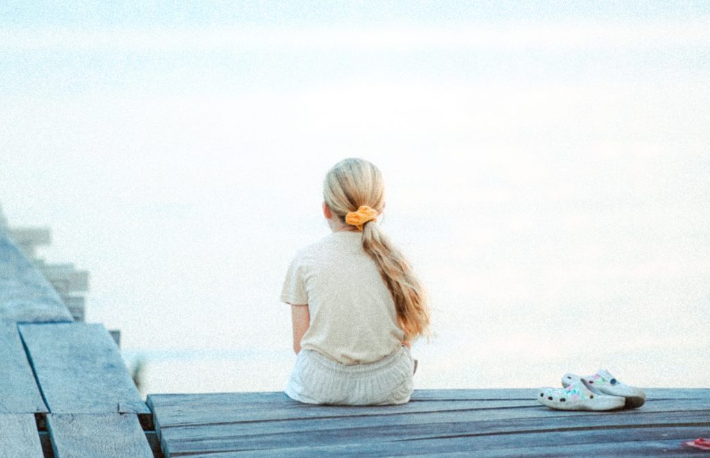 girl looking out at water because she doesn't want to go back to school