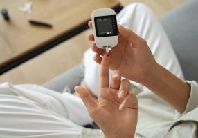 woman using a glucose meter to check diabetes